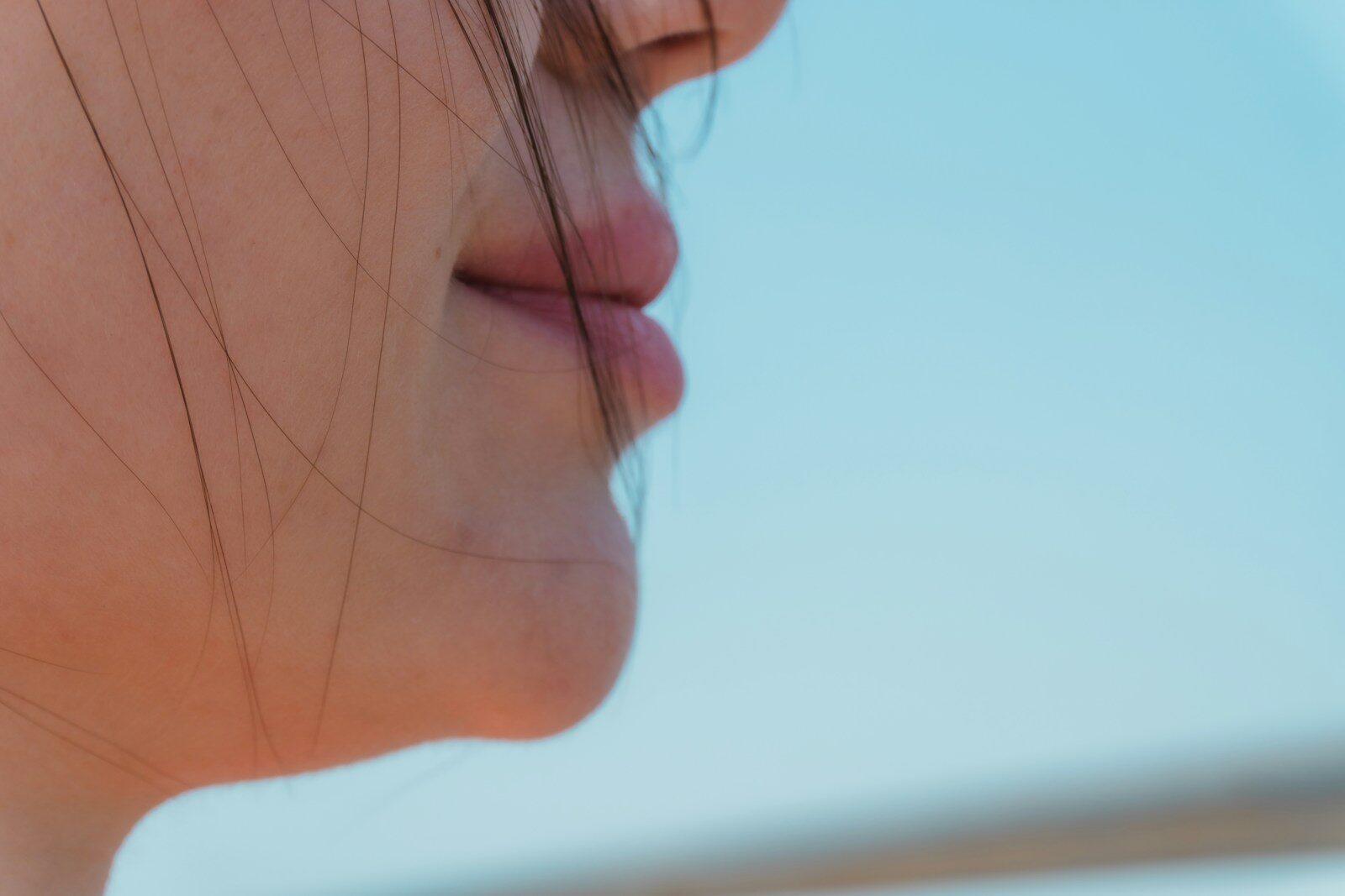Close-up of a woman's lips against a blue sky.