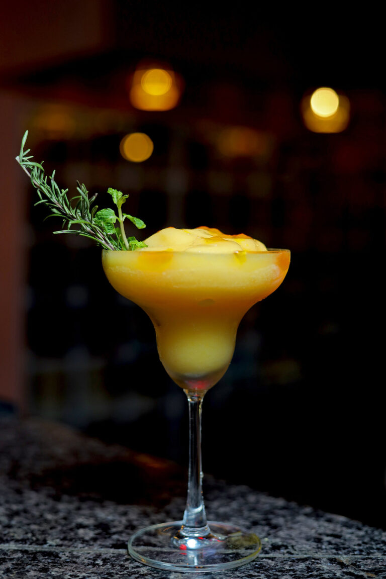 Frozen mango cocktail garnished with rosemary