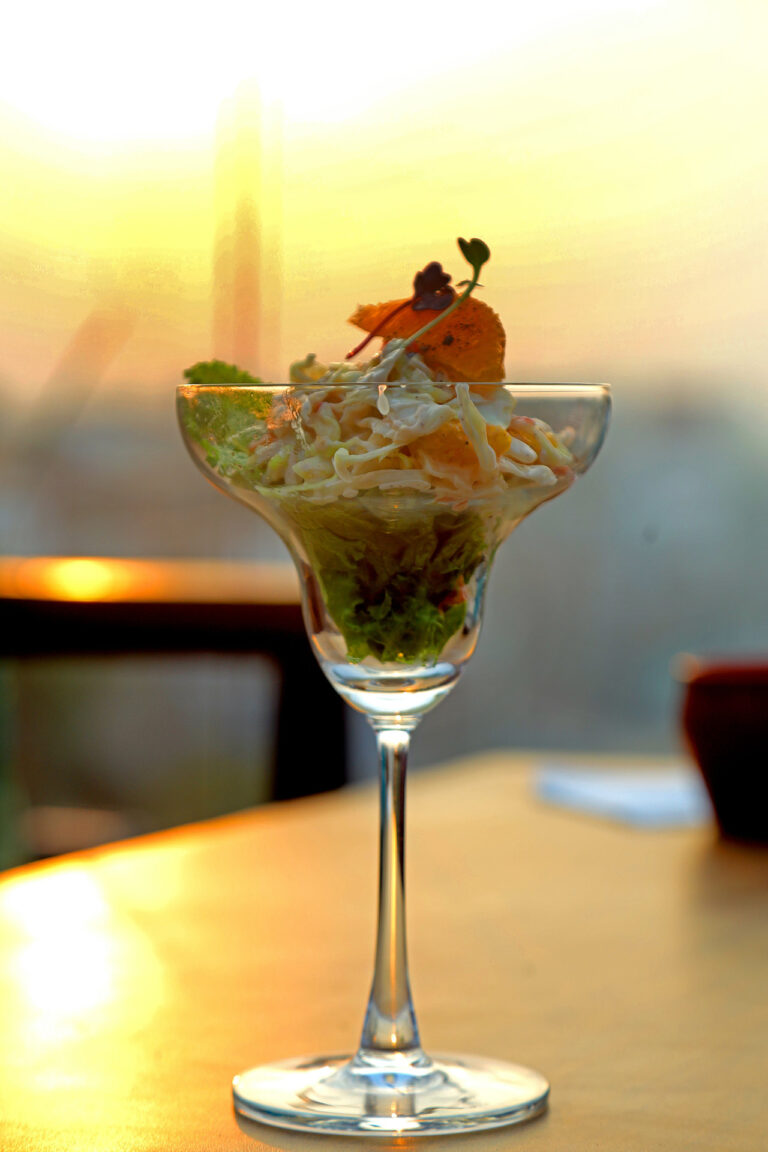 Salad in a cocktail glass on a rooftop at sunset