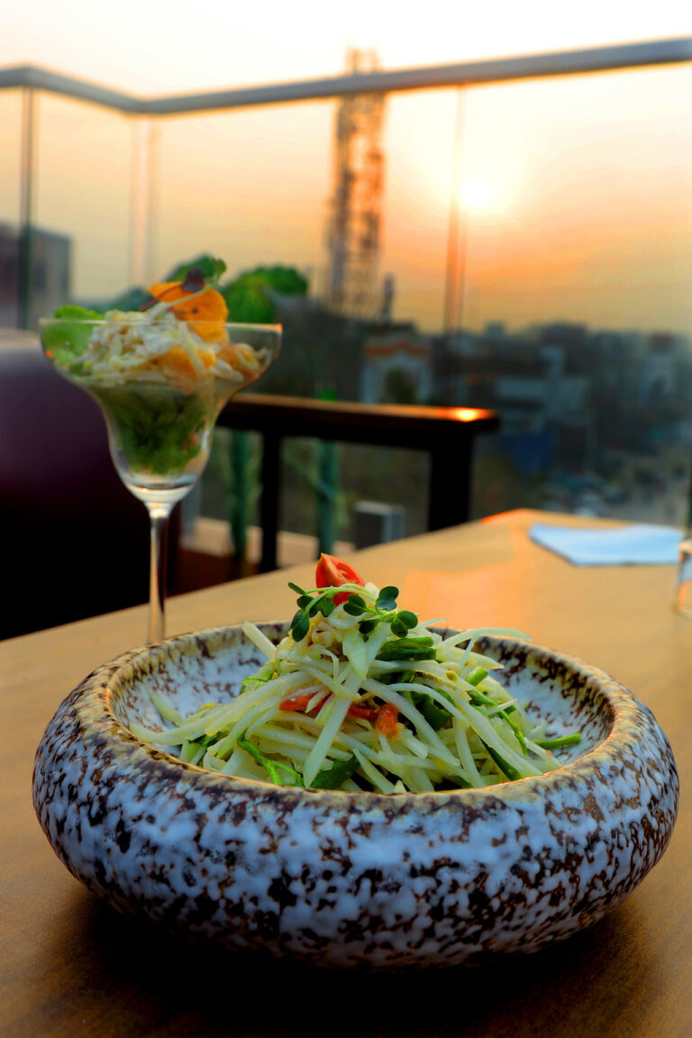 Raw papaya salad in a bowl against a sunset view